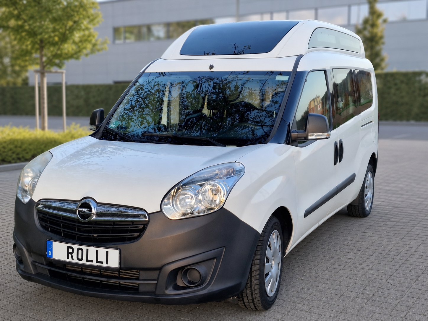 Rollstuhlgerechter Opel Combo mit Kennzeichen ROLLI vor neutralem Hintergrund
